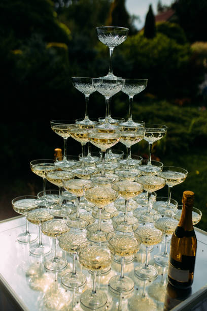 piramide di bicchieri da vino è sul tavolo al banchetto di nozze in giardino. - champagne wedding luxury dinner foto e immagini stock