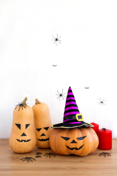istock Jack o Lantern with witch hat, spiders, red candles and Halloween squashes, vertical orientation 1346383075
