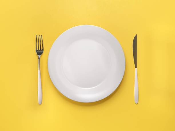 istock Empty plate with knife and fork  isolated on yellow  background 1346384080