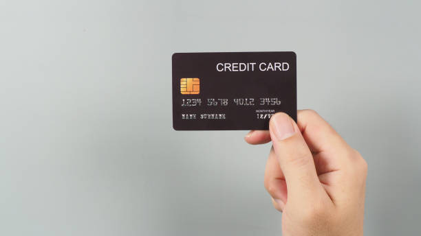 istock Hand is holding black credit card isolated on grey background. 1346384586