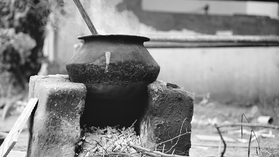 Water or something being boiled on a aluminum pan kept on a earthen oven with wood as fuel at a village in India.
