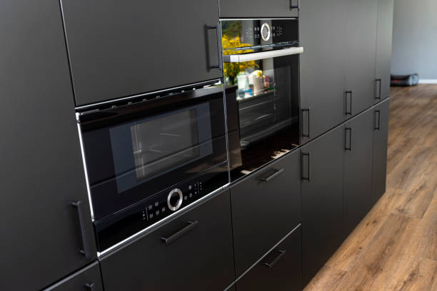 istock Modern kitchen with black fronts, built in oven and microwave, vinyl panels on the floor. 1346390580