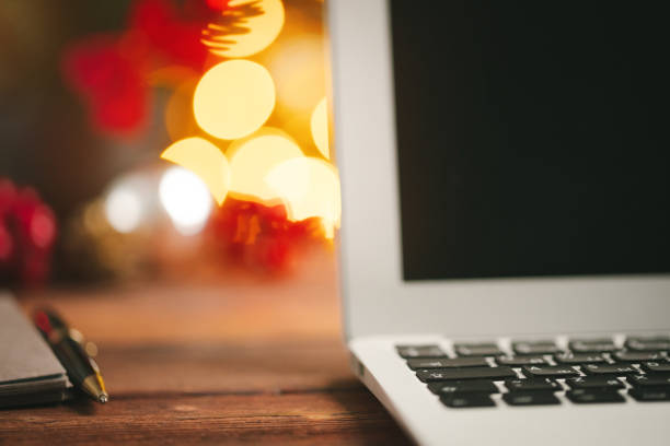 istock Wooden desk with computer with blank screen against blurred christmas lights background 1346393067
