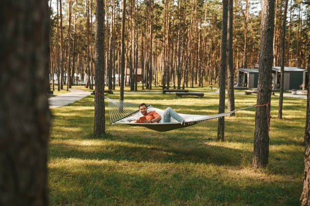 istock Smiling man with tablet relaxing in hammock 1346393780