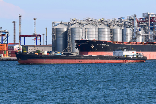 River lighter ARGO, having transshipped grain into the holds of the ocean-going bulk carrier CAPT STEFANOS at the grain terminal, leaves harbour for a new freight consignment. Port of Odessa. October 10, 2021