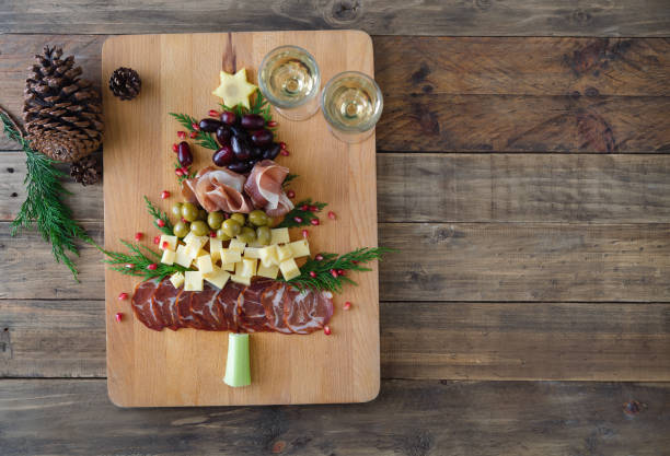 Christmas tree shaped cheese and charcuterie board with wooden background. Top view. Copy space. Christmas tree-shaped cheese and charcuterie appetizer board with wooden base. Top view. Copy space. charcuterie stock pictures, royalty-free photos & images