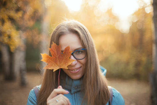 Autumn portrait of beautiful woman with maple leaves on fall nature background