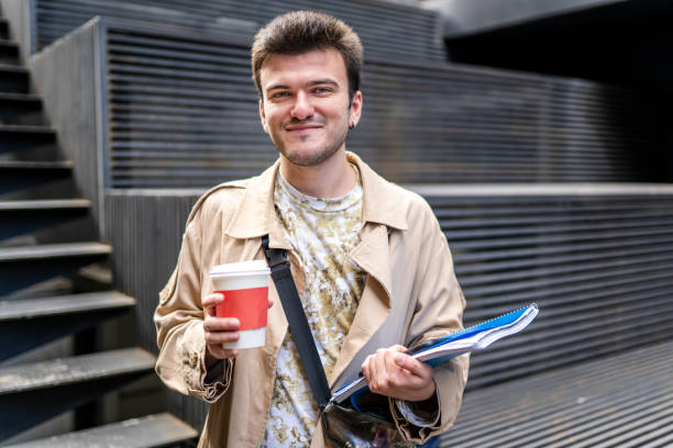 istock Image of young man on university campus and holding sustainable coffee cup 1346399604