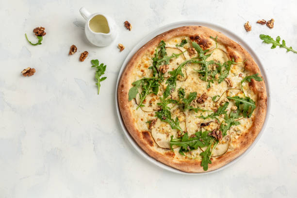 pizza with pear, blue cheese, walnut and arugula on light background. banner, menu, recipe place for text, top view