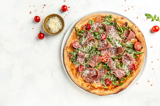 Delicious prosciutto ham pizza served with arugula and parmesan, Italian cuisine. banner, menu, recipe place for text, top view,