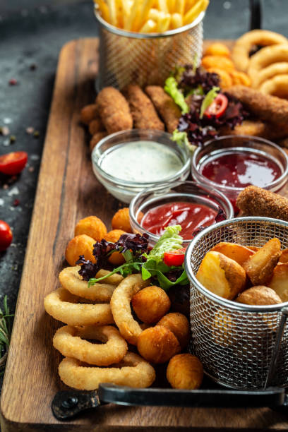pub appetizers fried mozzarella sticks, onion rings, french fries, chicken nuggets and sauce. vertical image. top view. place for text stock photo