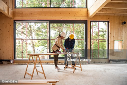 istock Female architect and construction worker looking at plans 1346403814