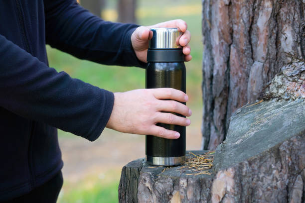 istock Tourist opening a vacuum thermos in the forest 1346404160