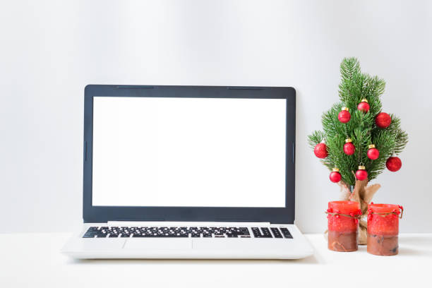istock Office workspace with laptop mockup screen, christmas tree, candle, supplies on a light background. Christmas home interior or office background 1346406921