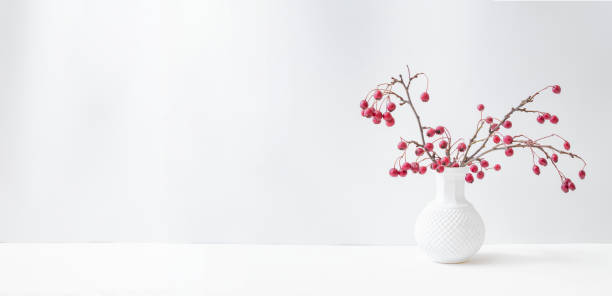istock Christmas, New Year home decor. Branches with red berries in a  vase on a light background. Mock up for displaying works 1346406925
