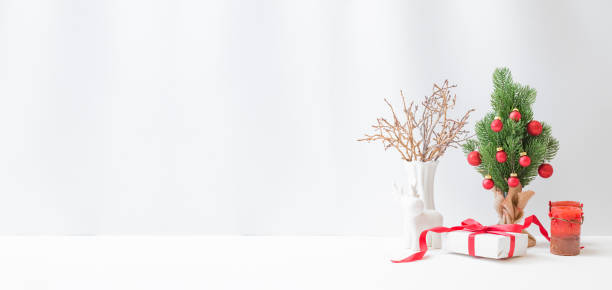istock Christmas, New Year home decor. Christmas tree, gift box, golden branches on a light background. Mock up for displaying works 1346406926