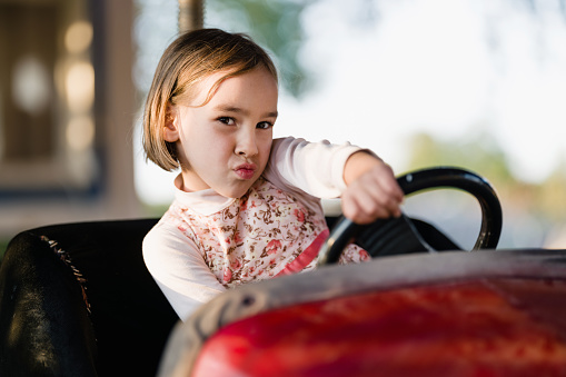 Little Child Girl driving Bumper Car, Playing At Playground Outdoors