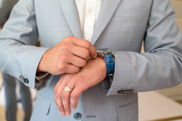 Closeup watch on businessman hand. Watch on the wrist of man in gray suit. Businessman checking time from watch. Hands of groom in suit getting ready for wedding. Groom holding watches observa de cerca de la mano de un hombre de negocios. mira en la muñeca del hombre con traje gris. hombre de negocios que verifica el tiempo desde el reloj. manos del novio en traje preparándose para la boda. relojes de sujeción de novios