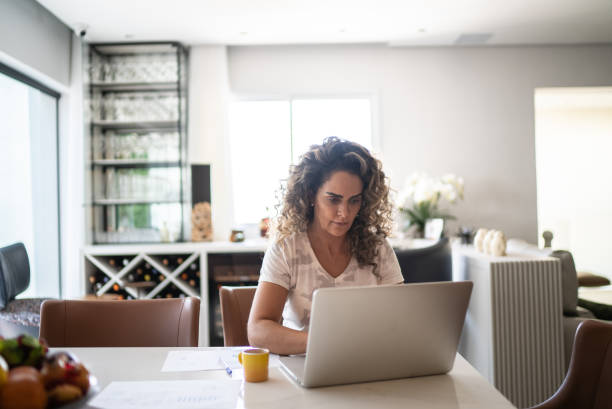 istock Mature woman using laptop working at home 1346412344