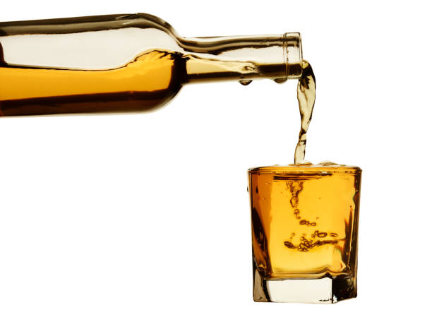 whiskey from the bottle is poured into a glass with bubbles and drops. isolated on a white background - shot glass glass alcohol color image imagens e fotografias de stock