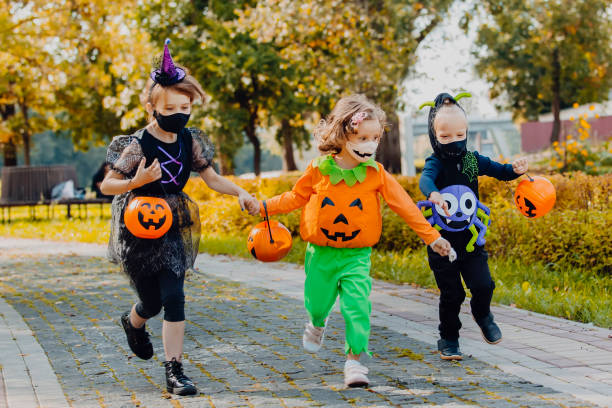 istock Happy Halloween. three running kids with a basket for sweets 1346413486