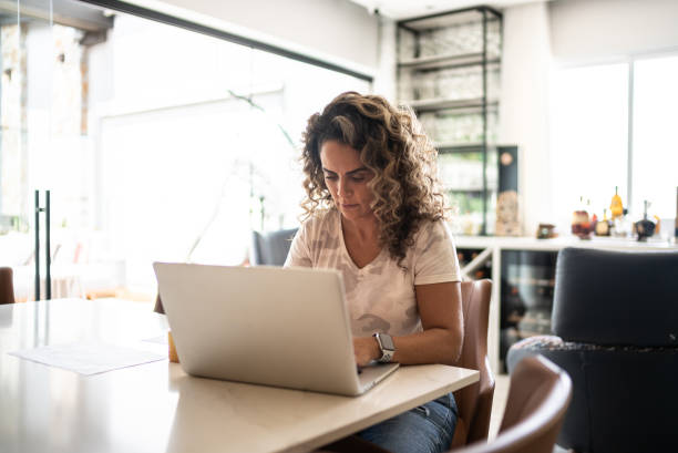 istock Mature woman using laptop working at home 1346413669
