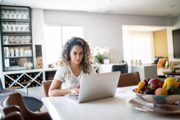 istock Mature woman using laptop working at home 1346414893