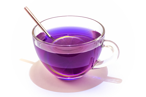 Cup of Anchan or Butterfly pea tea. Blue tea in a transparent glass cup with lime slice isolated on white background.