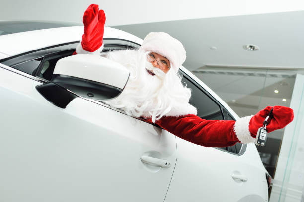 Santa climbs out of the window of a new white car and shows the car keys stock photo