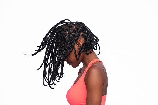 Side view of a young African American woman with her braids in the air while moving her head.