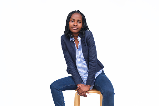 Businesswoman sitting on a stool in a studio with a white background.