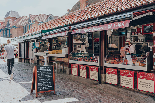 York, UK - June 22, 2021: Trader at the Swain Family Butchers market stall inside The Shambles Market, a daily market held in the city centre of York.