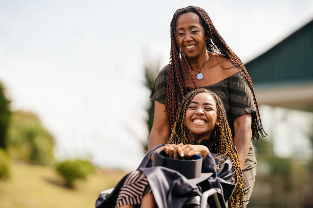 Mother taking her daughter in a wheelchair stock photo