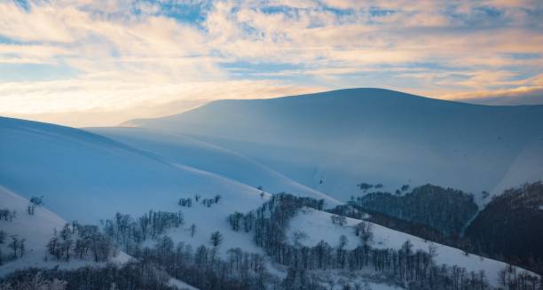 istock Fluffy clouds shelter under white snow sheltered by forests and beautiful mountains 1346423593