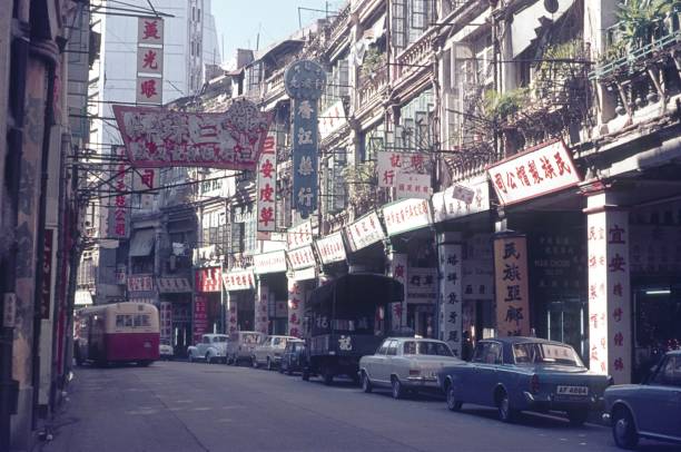 Street with old apartment buildings in British Hong Kong British Hong Kong, China, 1972. Street with old apartment buildings in British Hong Kong. Also: advertising signs and information, parked cars. chinese script photos stock pictures, royalty-free photos & images
