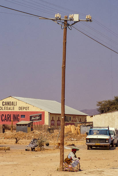 Old, rusted car wreck sits abandoned in a sunbaked desert. Open doors reveal a weathered cabin; barren landscape and clear blue sky create a striking, lonely scene.