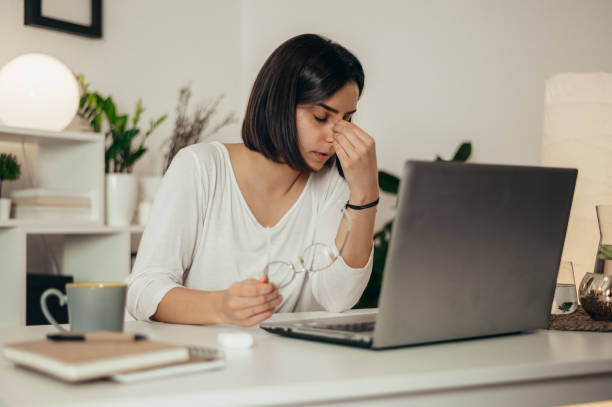 istock Woman feeling tired and stressed while using a laptop and working from home 1346428646