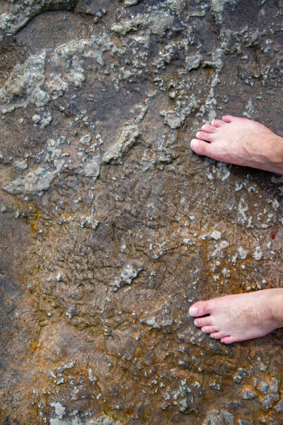 istock Feet standing on wet stone floor. Image suitable for the background 1346431340