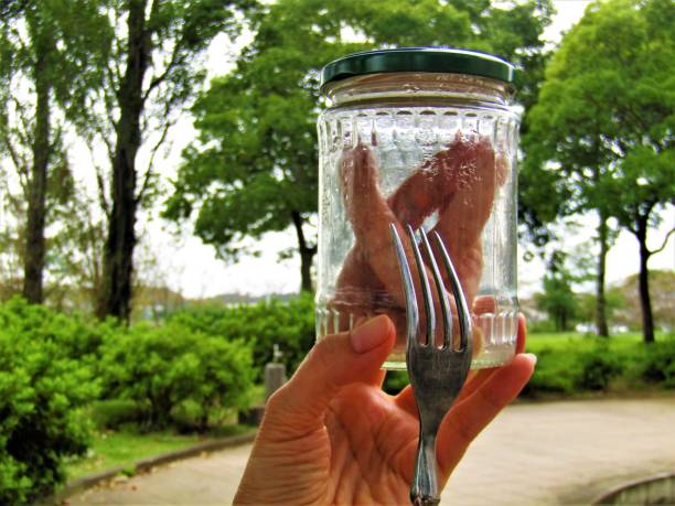 Close-Up Of Hand Holding Glass Jar Against Blue Background