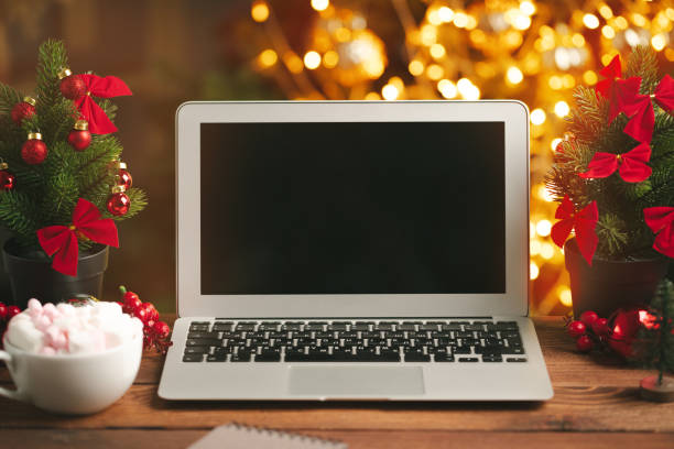 istock Wooden desk with computer with blank screen against blurred christmas lights background 1346432673