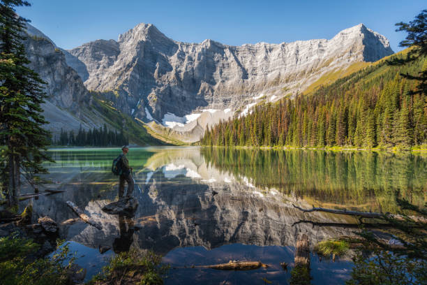 Senior Hiker Looking at View at Rawson Lake in Kananaskis, Alberta, Canada Senior Caucasian hiker looking at view at Rawson Lake during summer in Kananaskis Country, Alberta, Canada. rocky mountains banff alberta mountain stock pictures, royalty-free photos & images