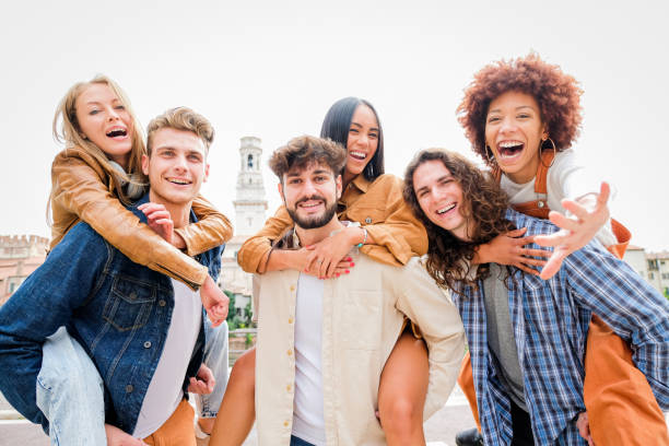 istock Young Friends having Fun Outdoors - Six students outdoors, men carrying two girls on their backs 1346433861
