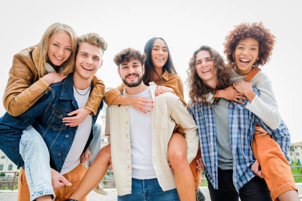 istock Young Friends having Fun Outdoors - Six students outdoors, men carrying two girls on their backs 1346433963