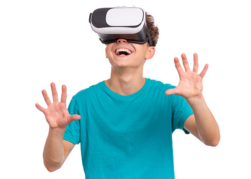 Portrait of young caucasian teen boy using virtual reality goggles. Funny teenager looking in VR glasses. Handsome child experiencing 3D gadget technology, isolated on white background