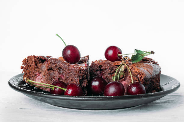 istock Chocolate brownie brownie on a black plate sprinkled with cherries. 1346435441