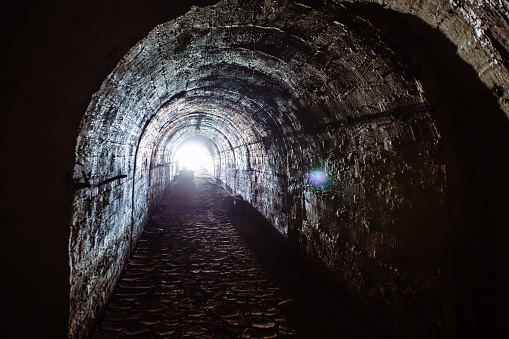 Dark underground tunnel. Light at the end of tunnel.