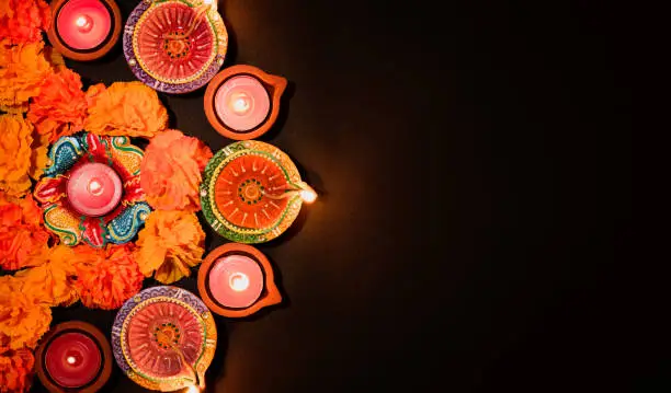 Photo of Happy Diwali - Clay Diya lamps lit during Dipavali, Hindu festival of lights celebration. Colorful traditional oil lamp diya on black background