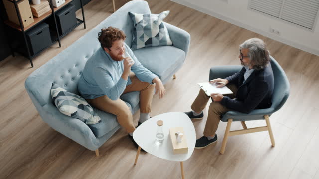 High angle view of men psychologist and patient talking sitting in modern office
