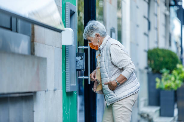 istock An Older Woman with Face Mask is Using ATM. 1346441846