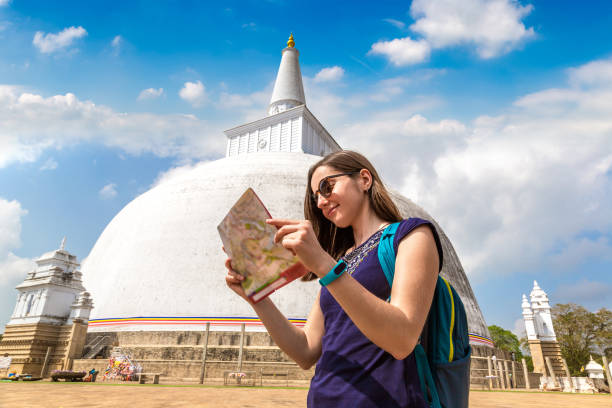 Woman holding a map near Big white Ruwanwelisaya stupa in Anuradhapura Archaeological Museum in Sri Lanka